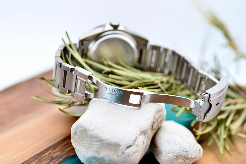 Tudor Pelagos 42 titanium bracelet clasp open, showing titanium engraving, styled with rocks and greenery