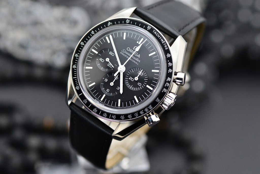 Omega Speedmaster Professional Moonwatch black chronograph dial with tachymeter bezel, three-quarter angled view on black leather strap