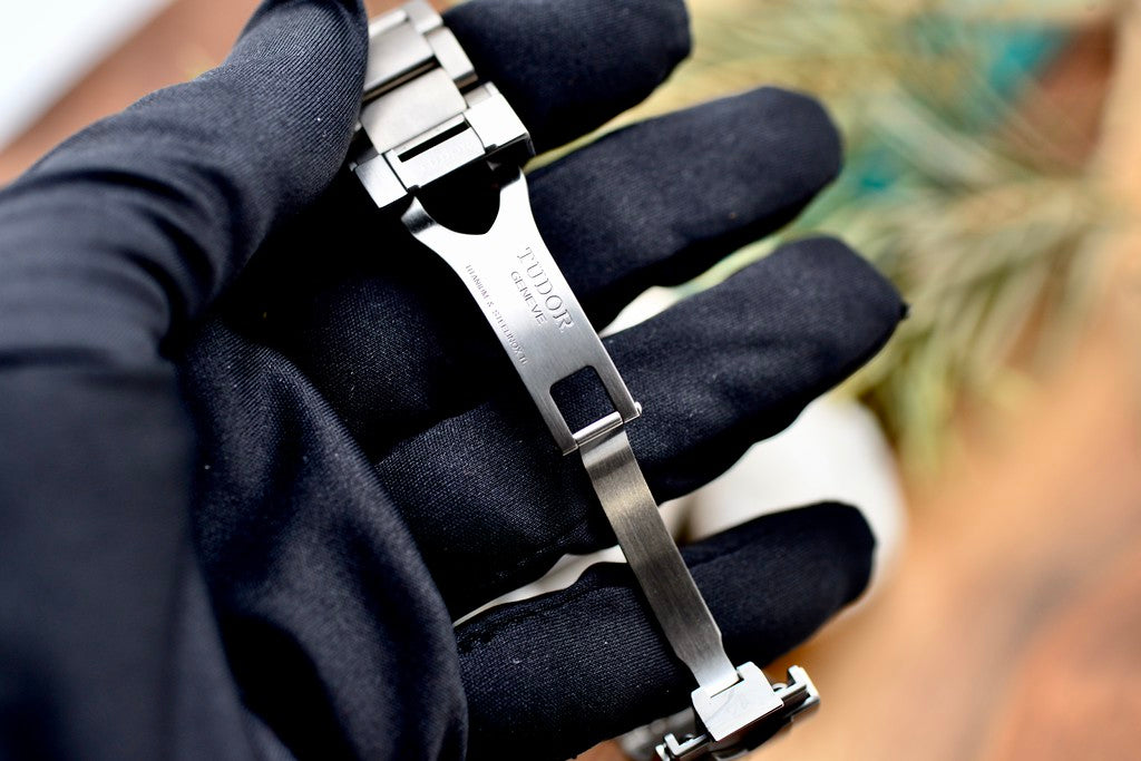 Tudor Pelagos 42 titanium folding clasp engraved with Tudor branding, held in a gloved hand