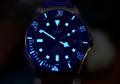 Tudor Pelagos 42 lume shot showing glowing blue luminous hands, hour markers, and bezel in the dark