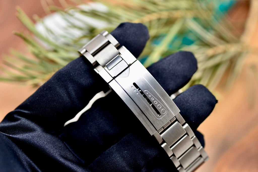 Tudor Pelagos 42 titanium bracelet and clasp held in a gloved hand, close-up