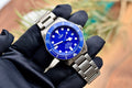 Tudor Pelagos 42 blue dial and titanium bracelet held in a gloved hand, angled presentation shot