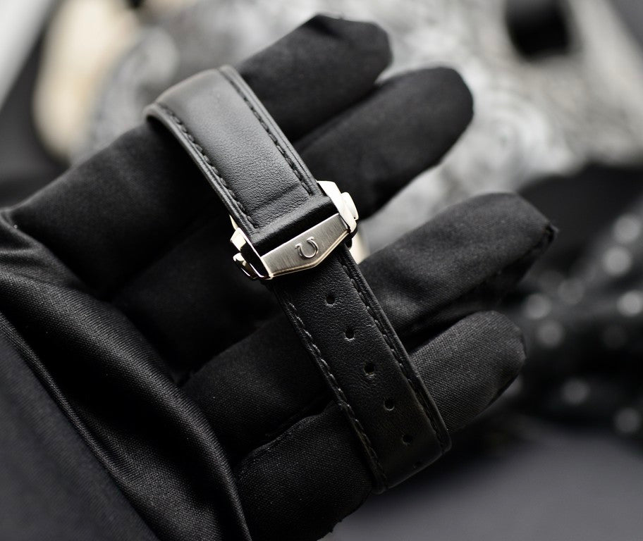 Omega Speedmaster Professional Moonwatch stainless steel buckle engraved with the Omega logo on black leather strap, close-up